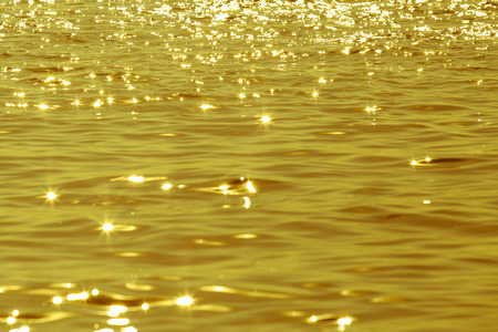 Sun light reflecting or sparkling glitter on water of sea or ocean at sunset or evening time with golden light tone.の写真素材