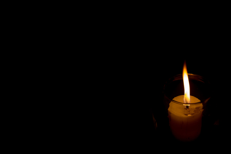 Candle fire light in glass isolated on dark or black background with copy space for your own text.の写真素材