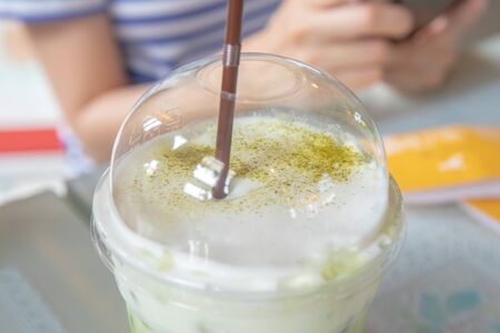Coffee with green tea with white milk cream foam at coffee shop.の写真素材