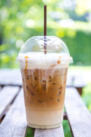 Coffee iced latte with milk in plastic glass on wooden table at coffee shop or vintage restaurant.の写真素材