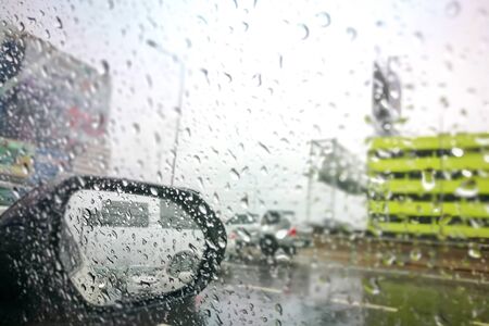 Road view through side car window mirror or rear view back with rain drops.の写真素材