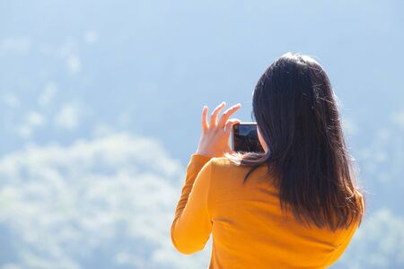Girl or women use mobile telephone to shooting a photo of mountain.の写真素材