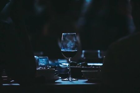 Closeup to wine glass at night party of wedding ceremony in dark tone.