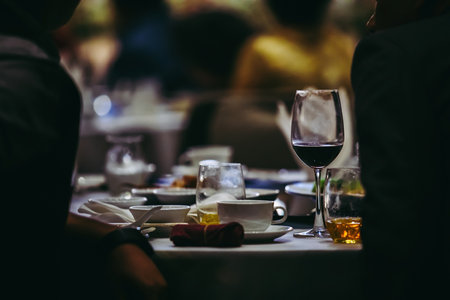 Closeup to wine glass at night party of wedding ceremony in dark tone.