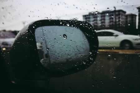 Road view through side car window mirror or rear view back with rain drops.の写真素材