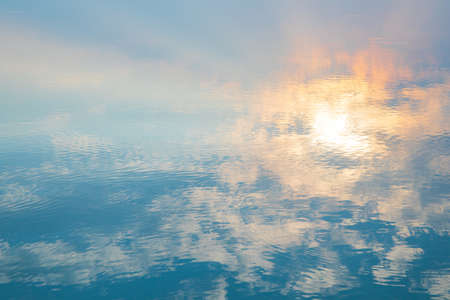 Water ripple circle on the surface of lake water with reflection of sky clouds at sunset or evenig time.の写真素材