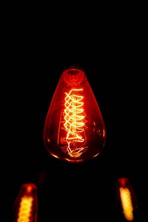 Incandescent electric light globe hang on the ceiling isolated on black background.