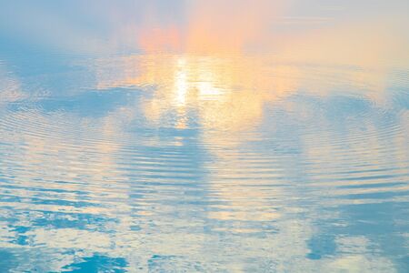 Water ripple circle on the surface of lake water with reflection of sky clouds at sunset or evenig time.の写真素材