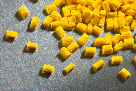 yellow polymer pellets on stainless steel sheet の写真素材