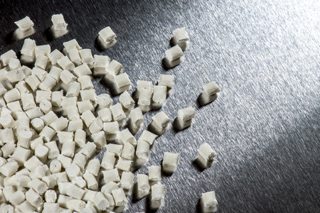 white polymer resin pellets on steel surface in factory