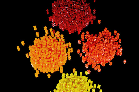 heaps of yellow, orange and red polmer resins on black background