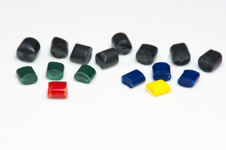 close up of several dyed plastic granules pellets on white