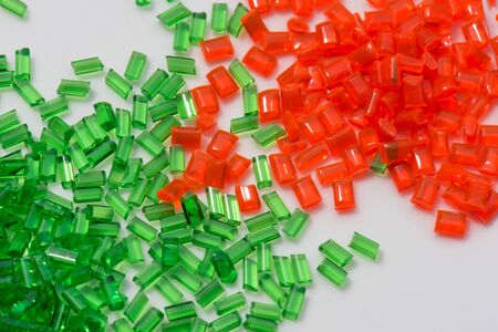red and green transparent polymer granulate on white background