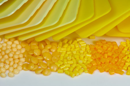different yellow plastic polymer resin granules with color samples plates in laboratory