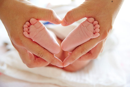 mother holding newborn baby feet of with heart shapeの写真素材