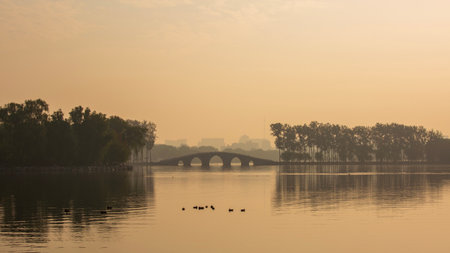The lake and arched bridge of Beijing's Yuyuantan Park shrouded in morning mist.の写真素材