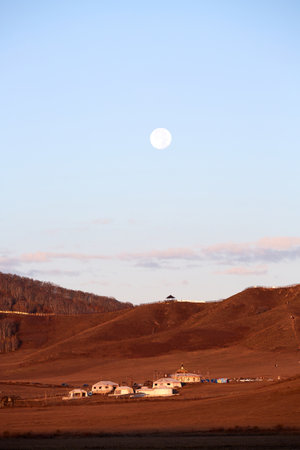 Sunrise over Mongolian yurts of herders under the full moon at Ulan Butong Grassland, Chinaの写真素材
