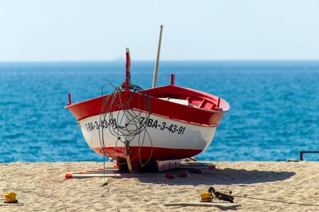 CALELLA, SPAIN - MAY 26, 2011: Red rowboat at the seaのeditorial素材