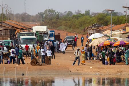 BAMBA TENDA, GAMBIA- JAN 6, 2014: Waiting people for the ferry. Also markets that sell everything around ferry docking placesのeditorial素材
