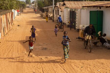 MARIAMA KUNDA, GAMBIA- JAN 9, 2014: For children is not much to do and when a truck is passing their street they will run behind itのeditorial素材