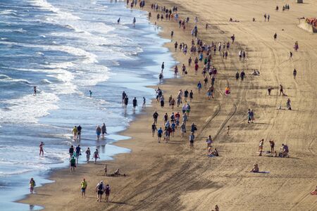 Tourists walk over the beachの写真素材
