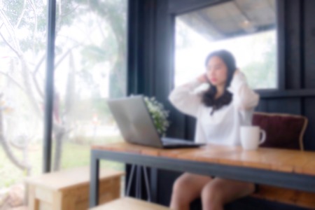 Blur portrait of girl who is  looking to laptop and slicnking her hair back.の写真素材