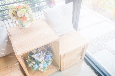 Two pillows on wooden desk with wooden stool and flower vasesの写真素材