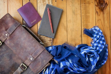 Leather brown bag passport and notebook with navy blue checked scarf.の写真素材