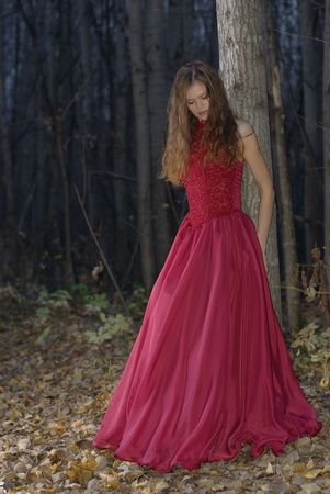 girl leaning against a tree in the twilight forestの写真素材