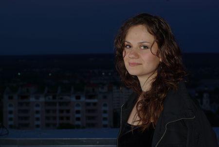 Girl in jacket and city in the twilightの写真素材