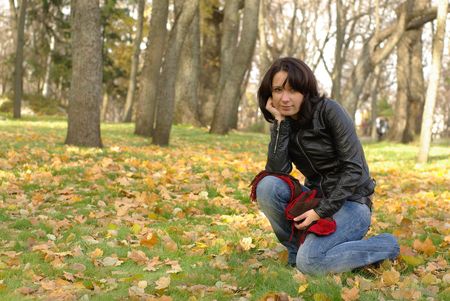female sitting on the green grass with yellow leavesの写真素材