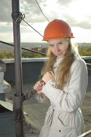 Smiling girl with a wrench in an orange helmetの写真素材
