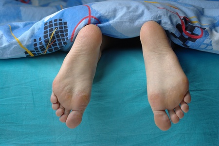 Female feet put out from the blanketの写真素材