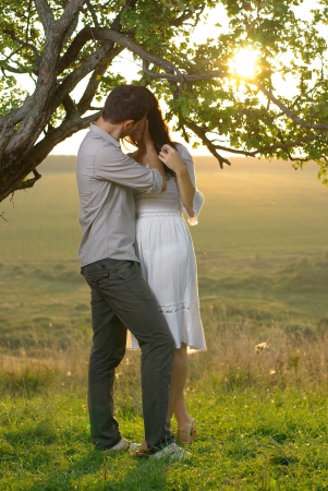 Couple kissing under tree at summer dayの写真素材