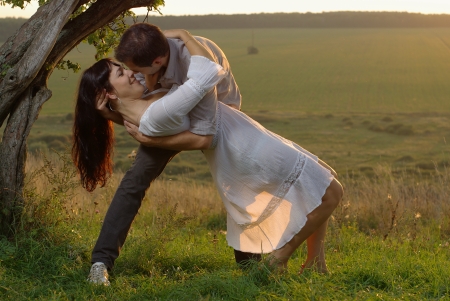 Two sweethearts kissing under tree on fieldの写真素材