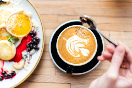 Breakfast Cup Of Coffee. Point of view of a woman's hand adding brown sugar to coffee on the dining table. Eating out lifestyleの写真素材