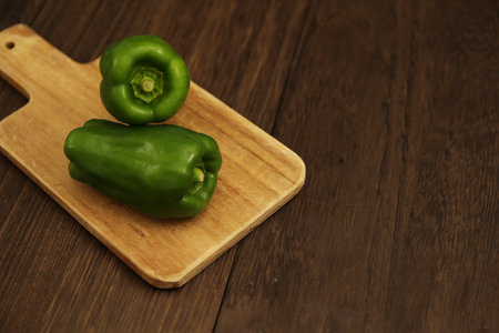 Multiple peppers on a cutting board on a wooden tableの写真素材