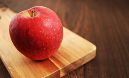 One apple on a cutting board on a wooden tableの写真素材
