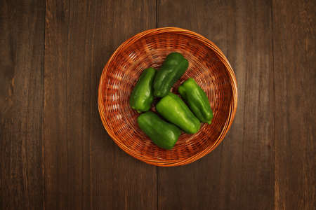 Multiple peppers in a colander on a wooden tableの写真素材