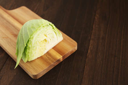 One cabbage cut on a cutting board on a wooden tableの写真素材