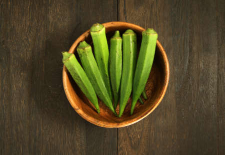multiple okras in a bowl at a wood-grained tableの写真素材