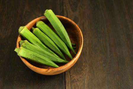multiple okras in a bowl at a wood-grained tableの写真素材