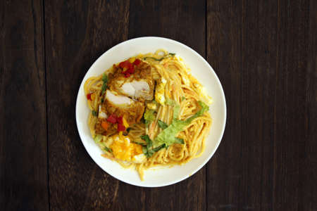 Curry pasta with tandoori chicken placed on a wooden tableの写真素材