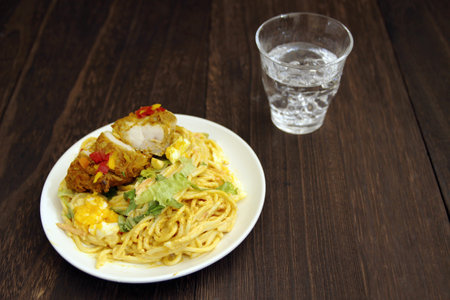 Curry pasta with tandoori chicken placed on a wooden tableの写真素材