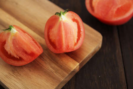 Cut tomatoes placed on a wooden chopping boardの写真素材