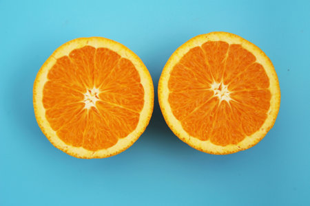 Half-cut orange placed on a light blue backgroundの写真素材