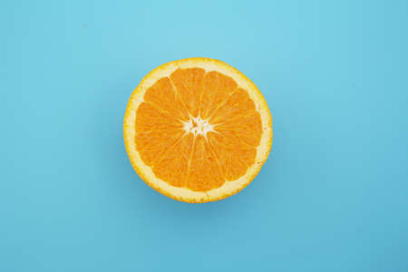 Half-cut orange placed on a light blue backgroundの写真素材