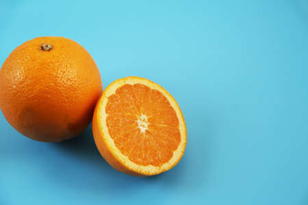 Half-cut orange placed on a light blue backgroundの写真素材