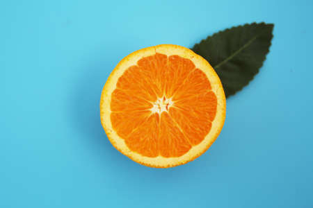 Half-cut orange placed on a light blue backgroundの写真素材