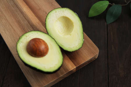 Avocado cut in half on a wooden tableの写真素材